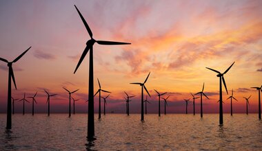 A series of wind turbines against a sunset 